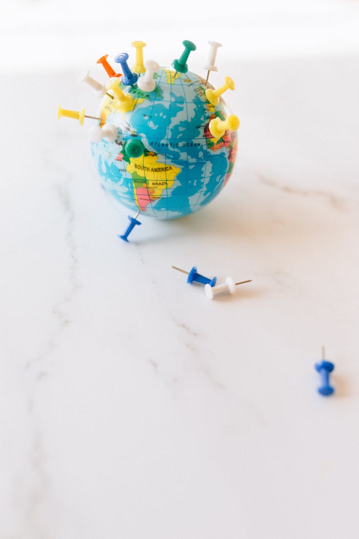 A small globe adorned with colorful pins, symbolizing travel and world exploration.